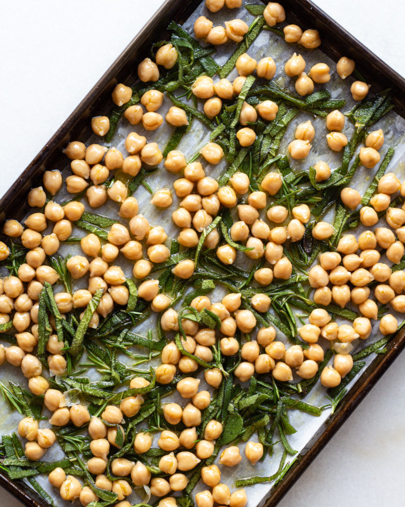 sage and rosemary on baking sheet with chickpeas