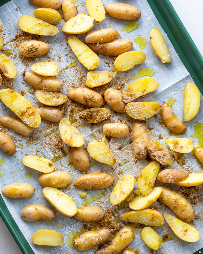 Sliced and seasoned potatoes on baking sheet