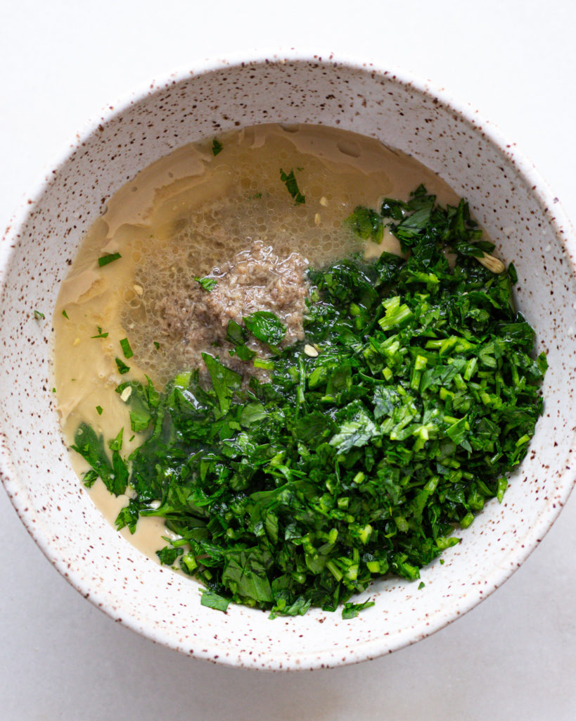 All ingredients for anchovy tahini dressing in bowl
