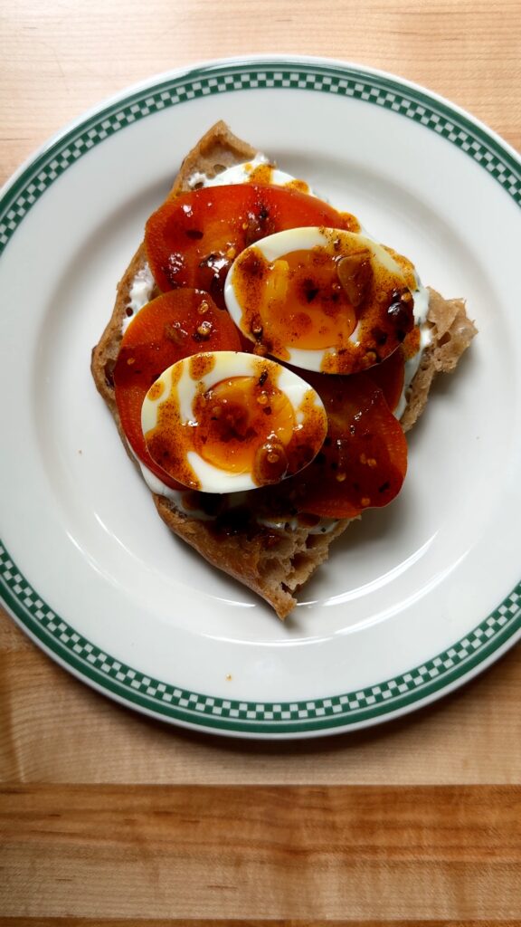 Paprika garlic oil spread on top of the elements of the çilbir sandwich