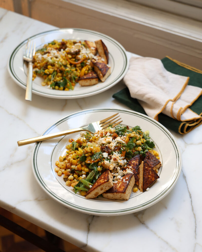 corn and scallion salad on two plates, ready to serve