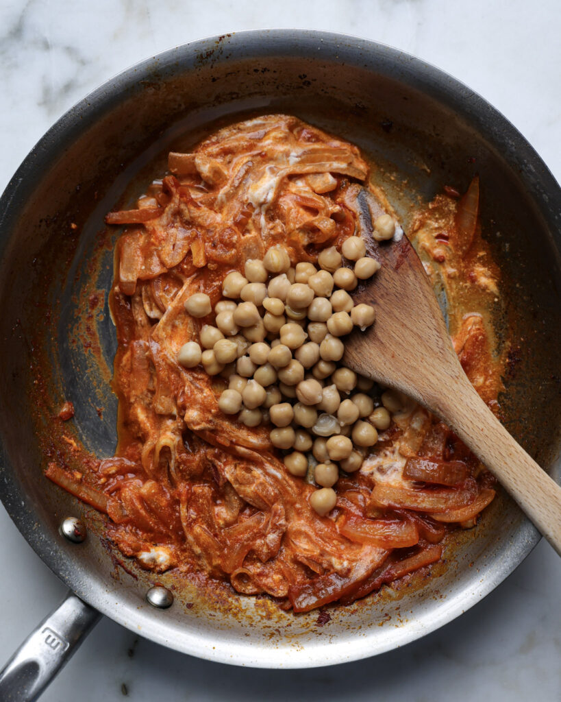 chickpeas in a pan being added to vodka sauce.