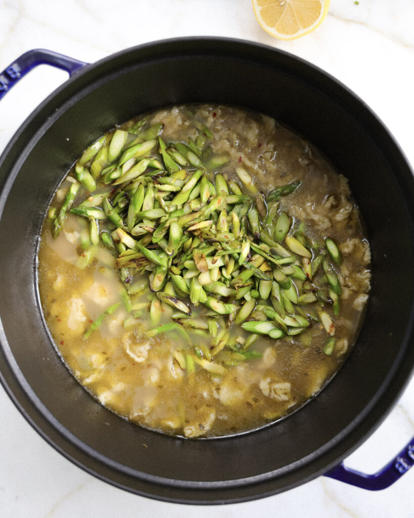 Asparagus added to a pot with spaetzle.