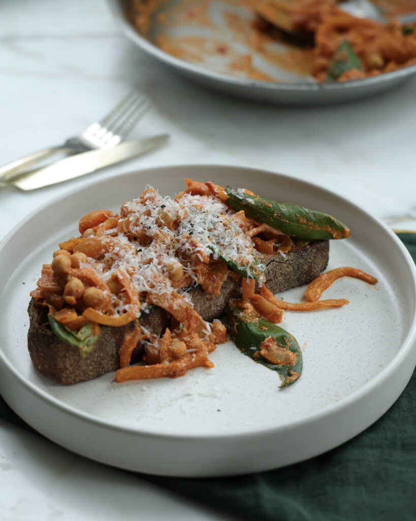 Beans alla vodka on toast topped with parmesan