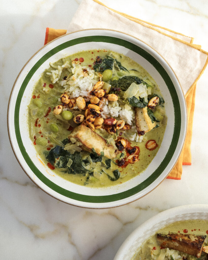 winter vegetables green soup in a bowl topped with chili peanuts