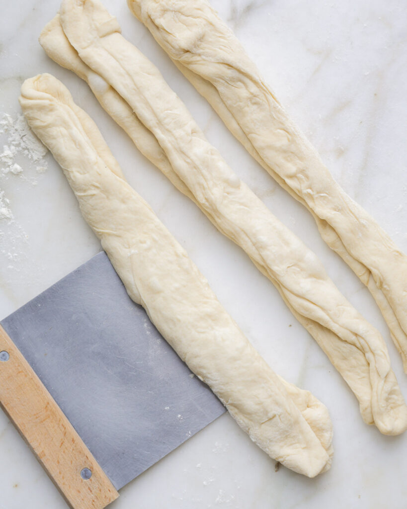 vegan brioche dough being shaped into a braided loaf.