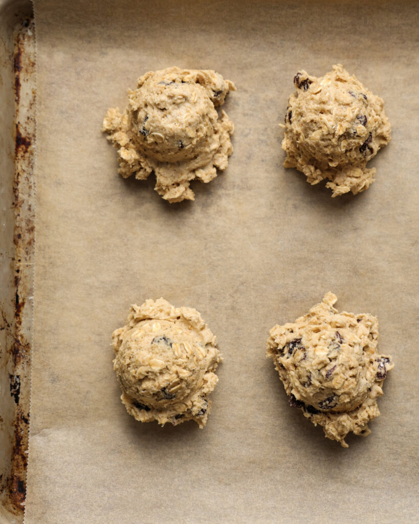 brown butter oatmeal raisin cookie dough scooped onto a baking sheet.