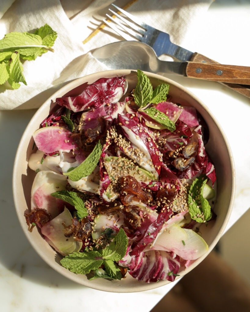 Lemon tahini salad topped with sesame seeds and mint in a bowl.