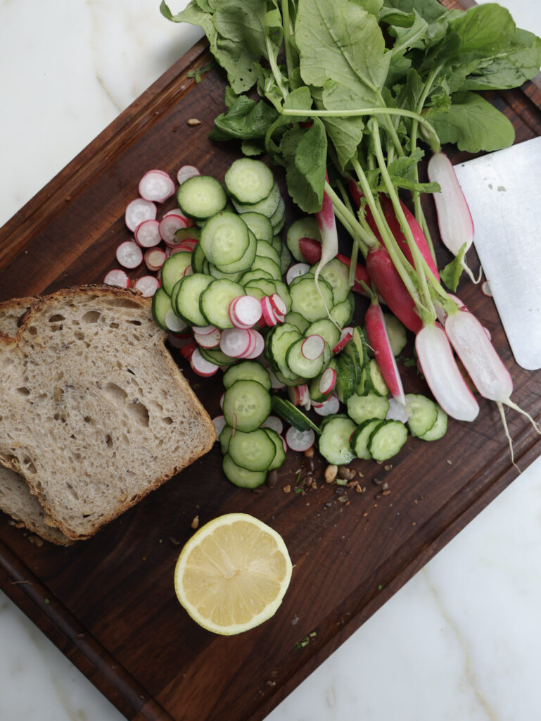 radishes, cucumbers and bread on a cutting board.