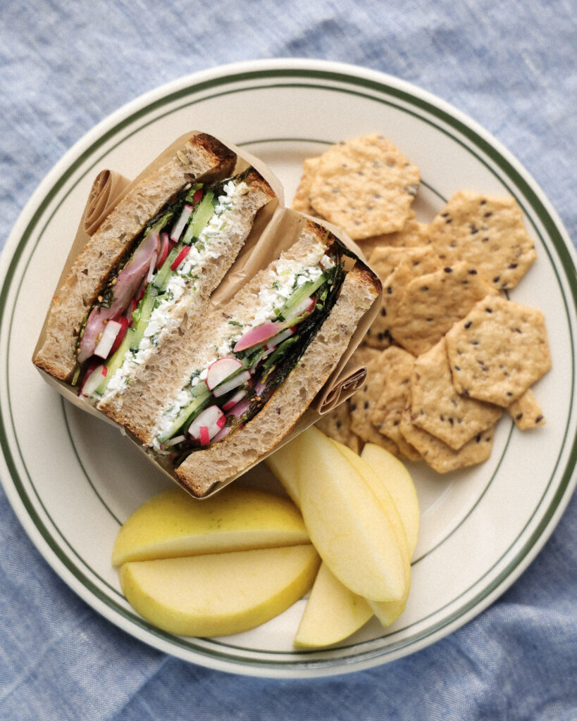 Radish sandwich on a plate served with crackers and apples