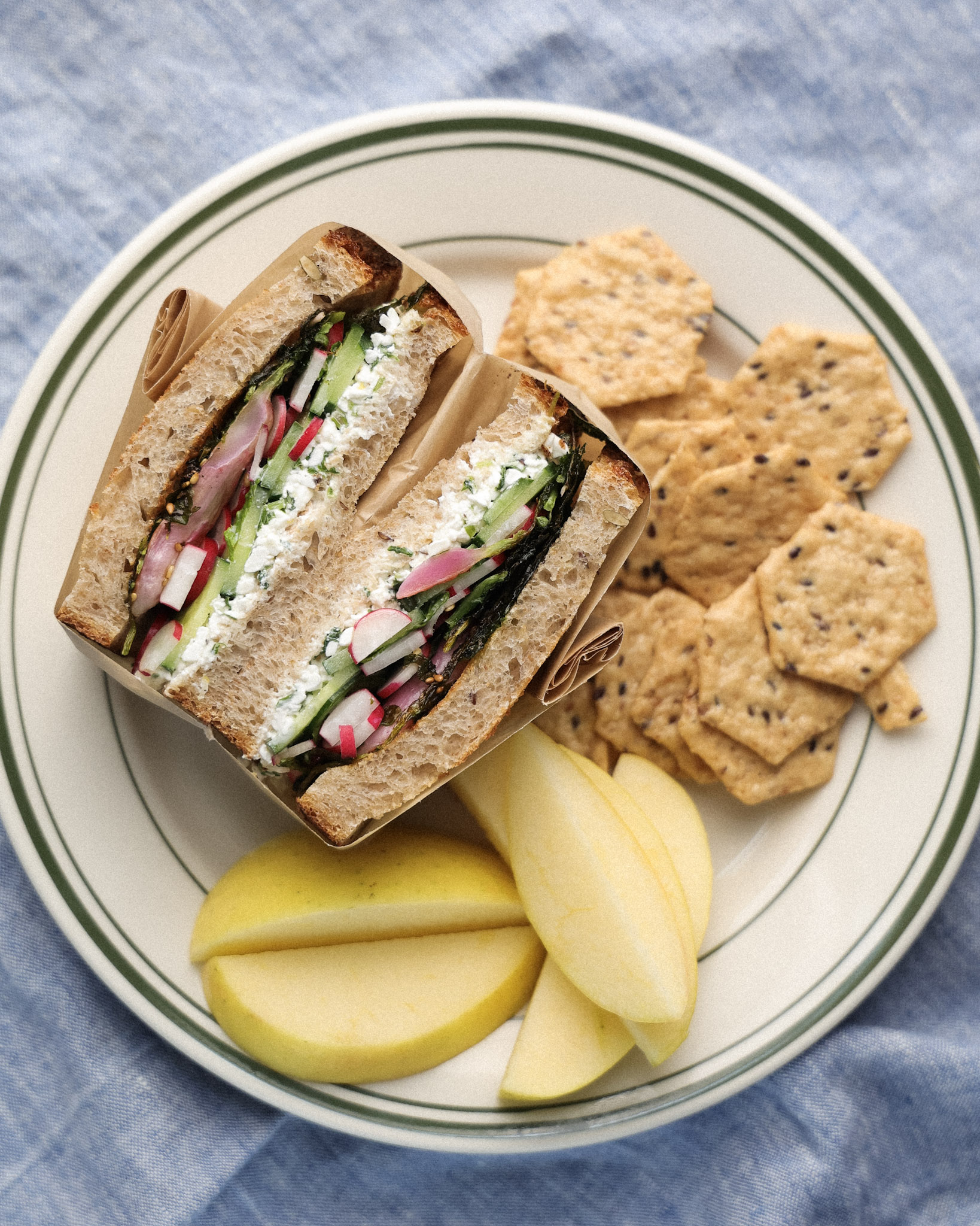 Radish sandwich on a plate served with crackers and apples