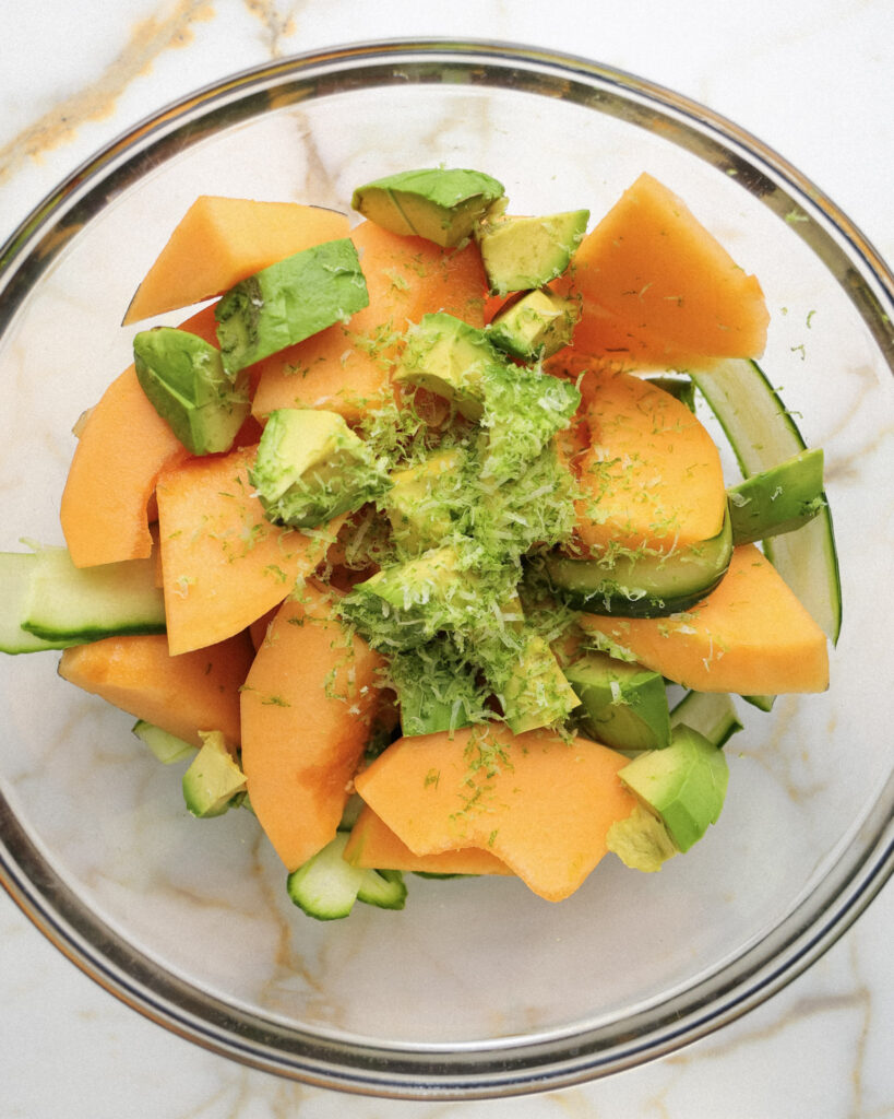 cucumber, melon, lime zest and avocado in a bowl.