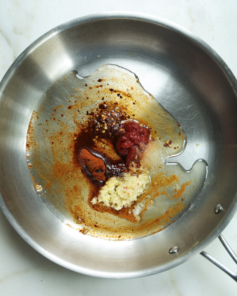 Oil, spices and tomato paste in a pan.