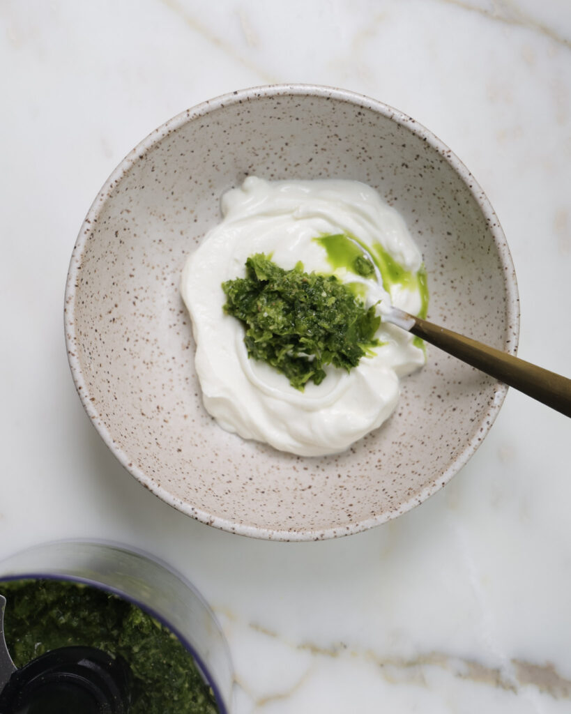 Green sauce being mixed into skyr.