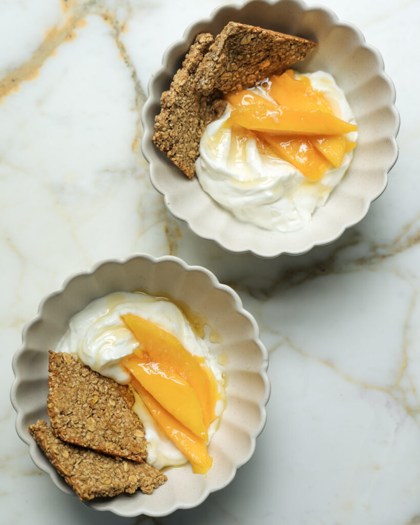 Granola bark in a bowl with yogurt and mango slices.