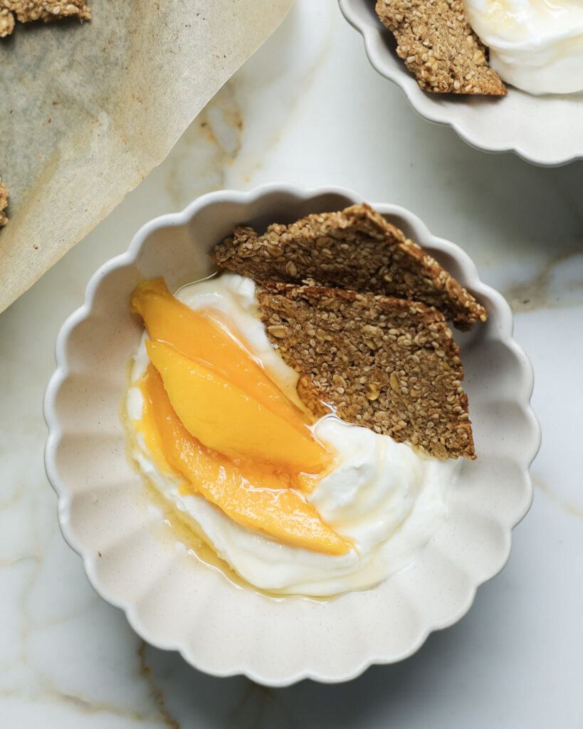 Granola bark in a bowl with yogurt and mango slices.