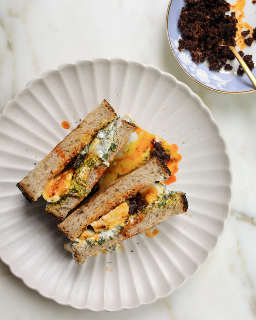 Çilbir sandwich halved on a plate.