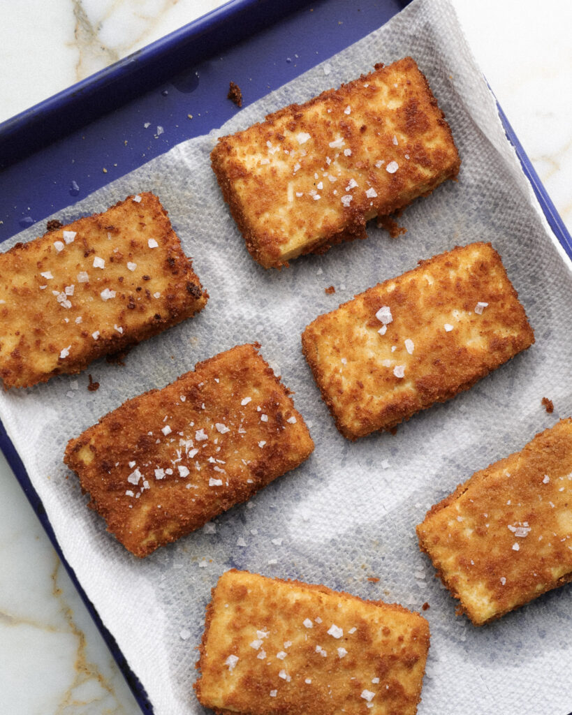 Fried tofu cutlets on a paper towel.