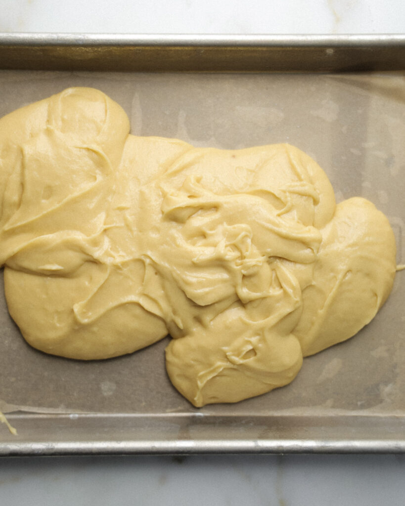 Yellow cake layer being poured into a baking sheet