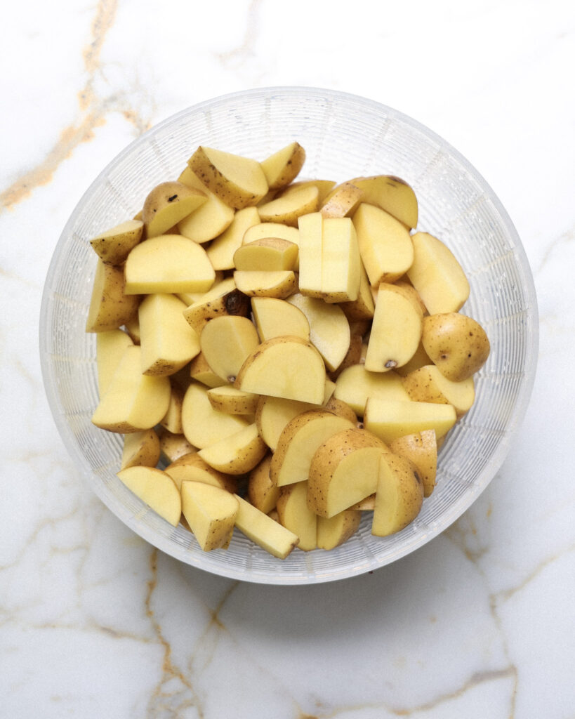 Russet potatoes cut into half moons for potato salad.