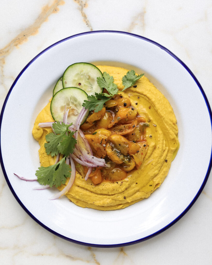 Hummus topped with sungold tomatoes, veggies and herbs.