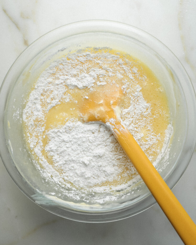 Powdered sugar being mixed into ingredients for gooey butter layer.