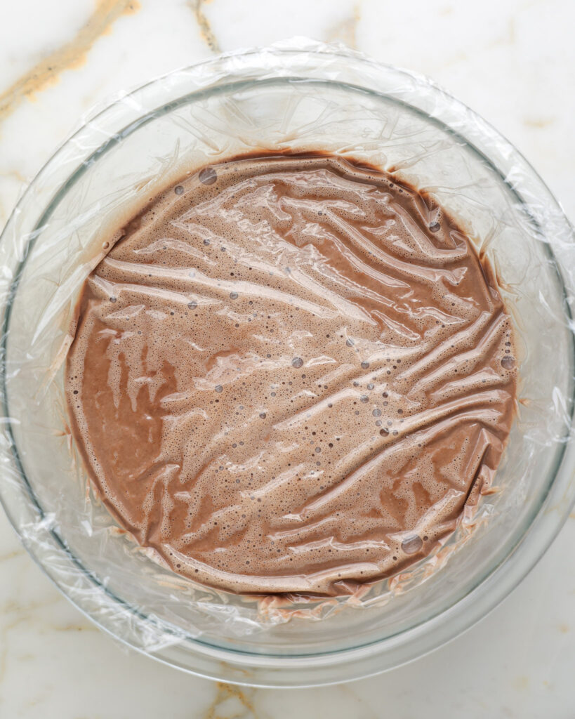 Chocolate ice cream with cling wrap on it before freezing.