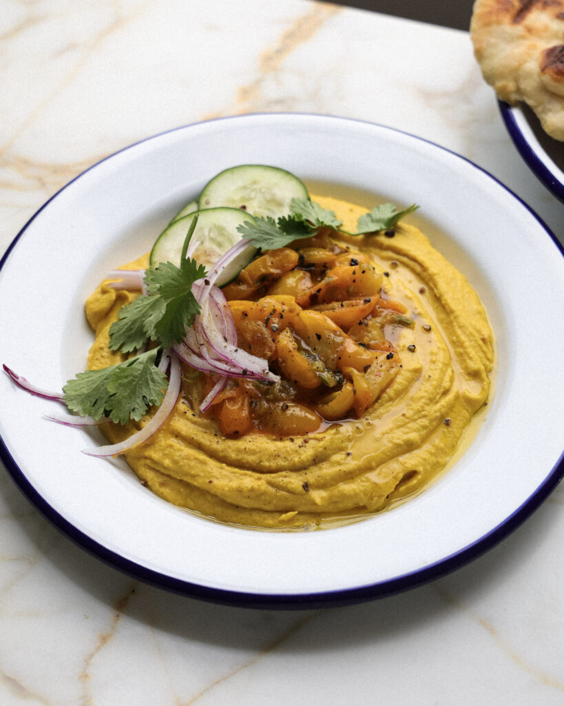 Hummus topped with sungold tomatoes, veggies and herbs.