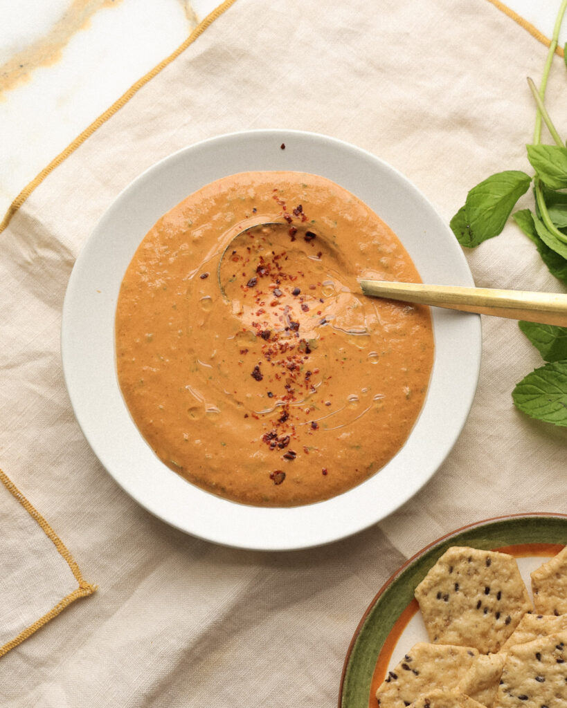 Romesco in a bowl topped with red pepper flakes and oil.