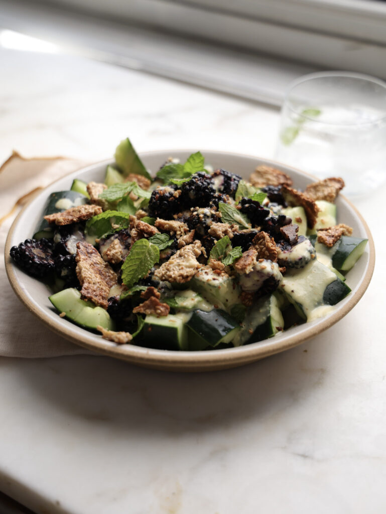 Smashed cucumber and blackberry salad in a bowl.