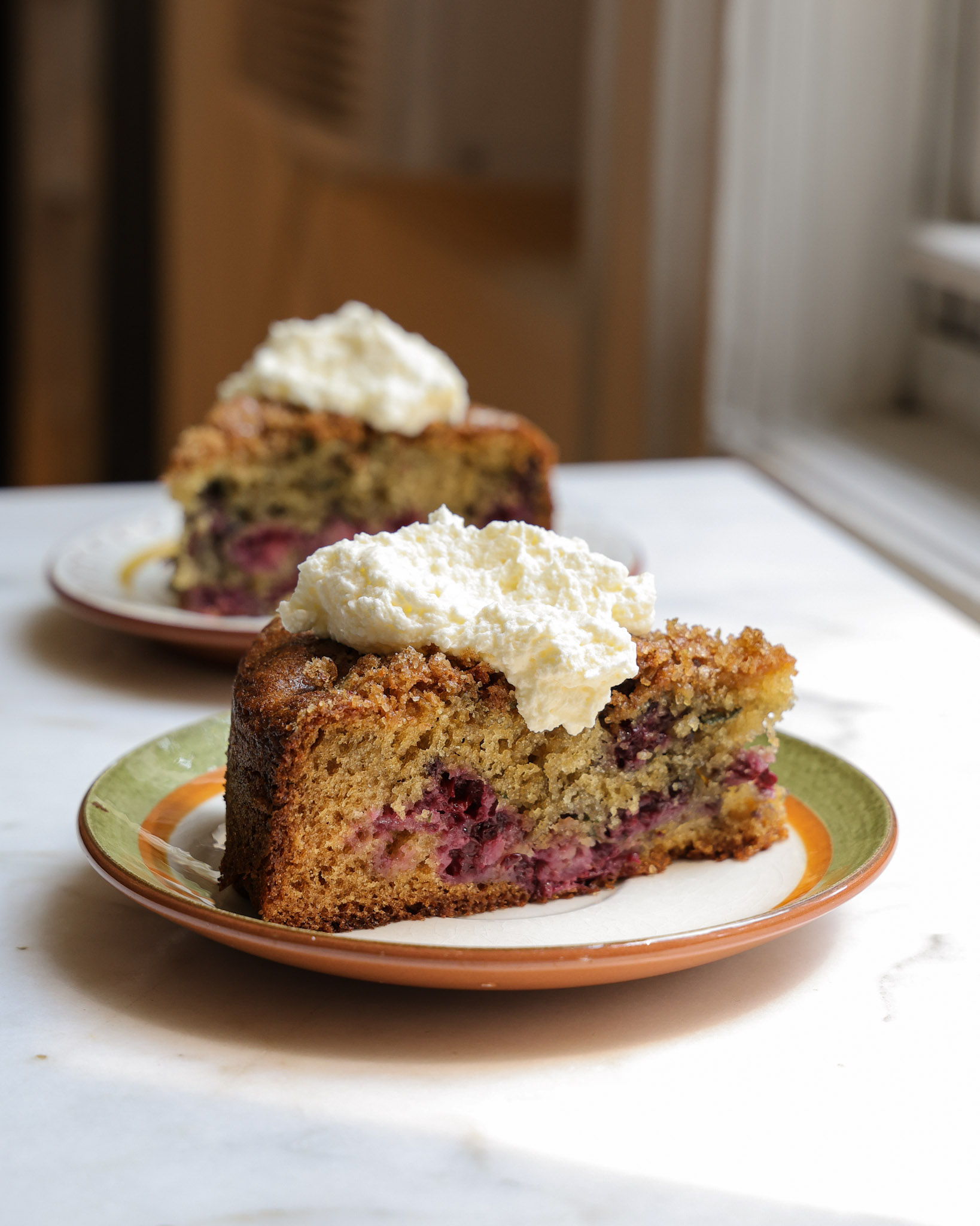 A slice of blackberry cake topped with whipped cream.