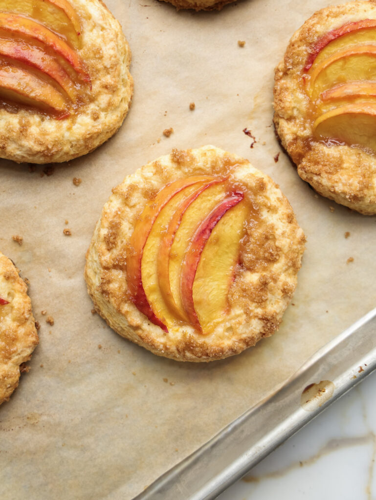 Baked peach shortcakes on a baking sheet.